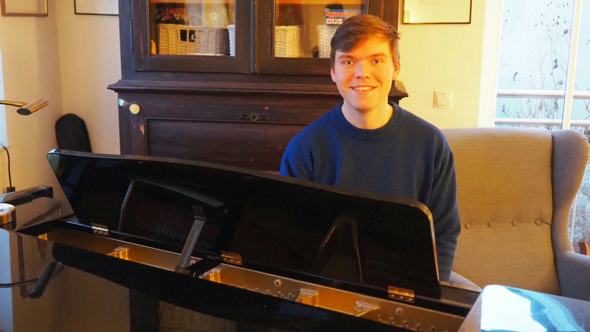 Kilian Günthner sitzt hinter einem Flügel und grinst in die Kamera.