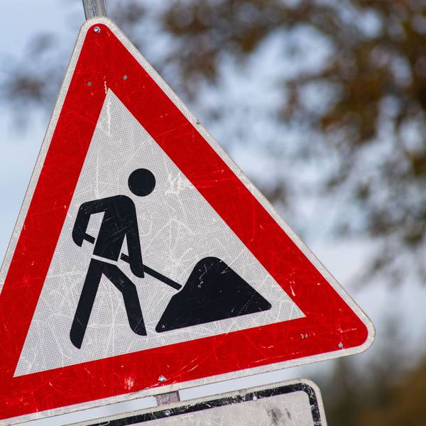 Das Foto zeigt ein zerkratztes Schild mit dem Piktogramm eines Bauarbeiters zur Beschilderung einer Baustelle.