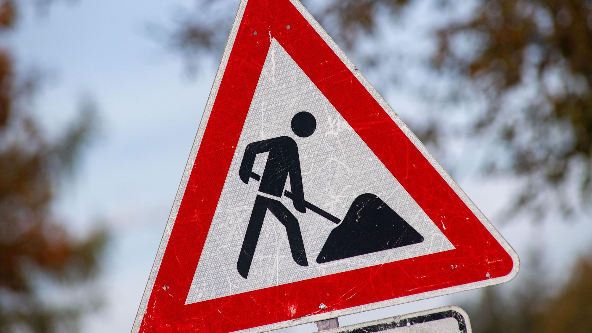 Das Foto zeigt ein zerkratztes Schild mit dem Piktogramm eines Bauarbeiters zur Beschilderung einer Baustelle.