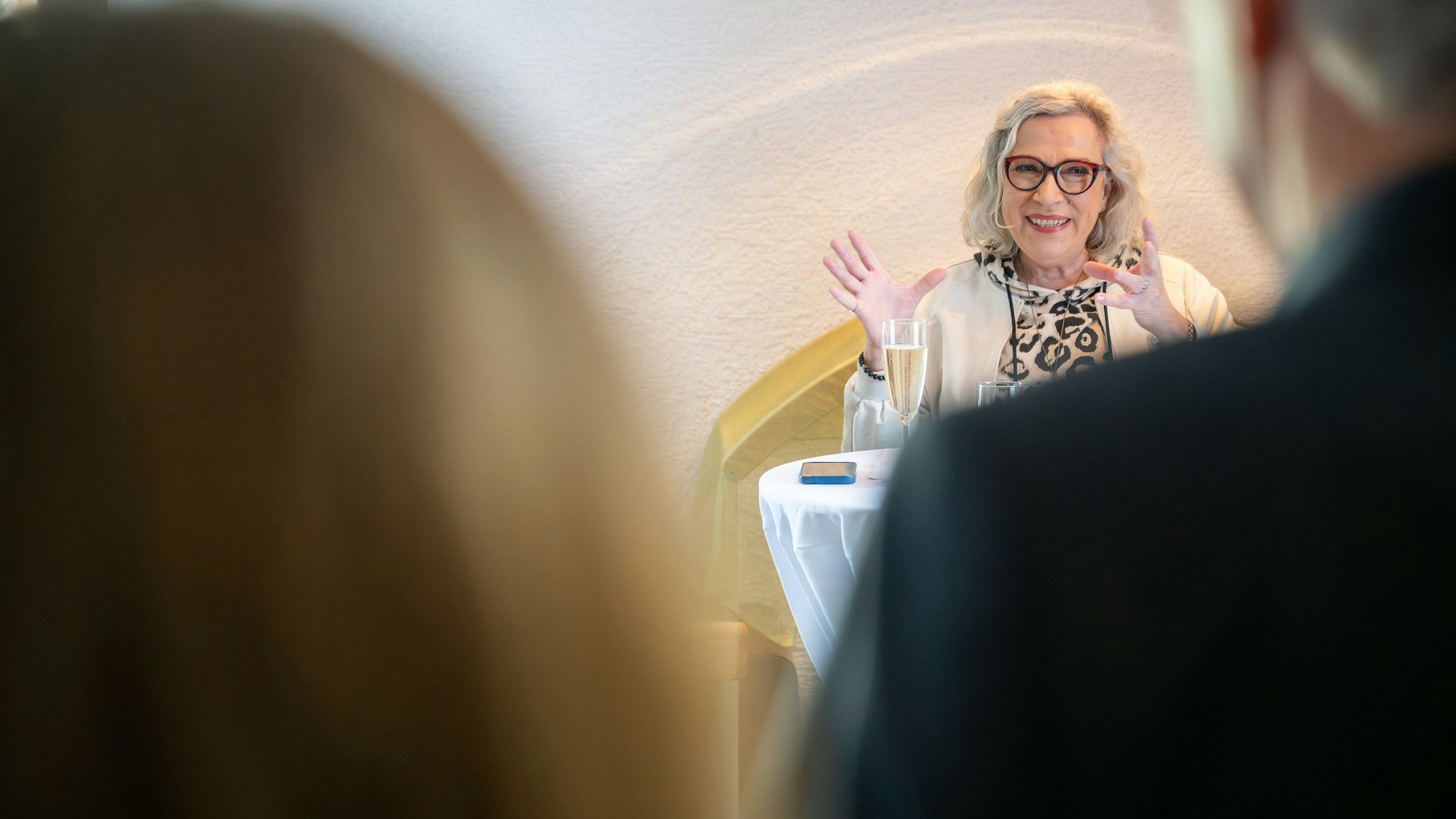 Eine Dame gestikuliert mit den Händen und lächelt dabei.