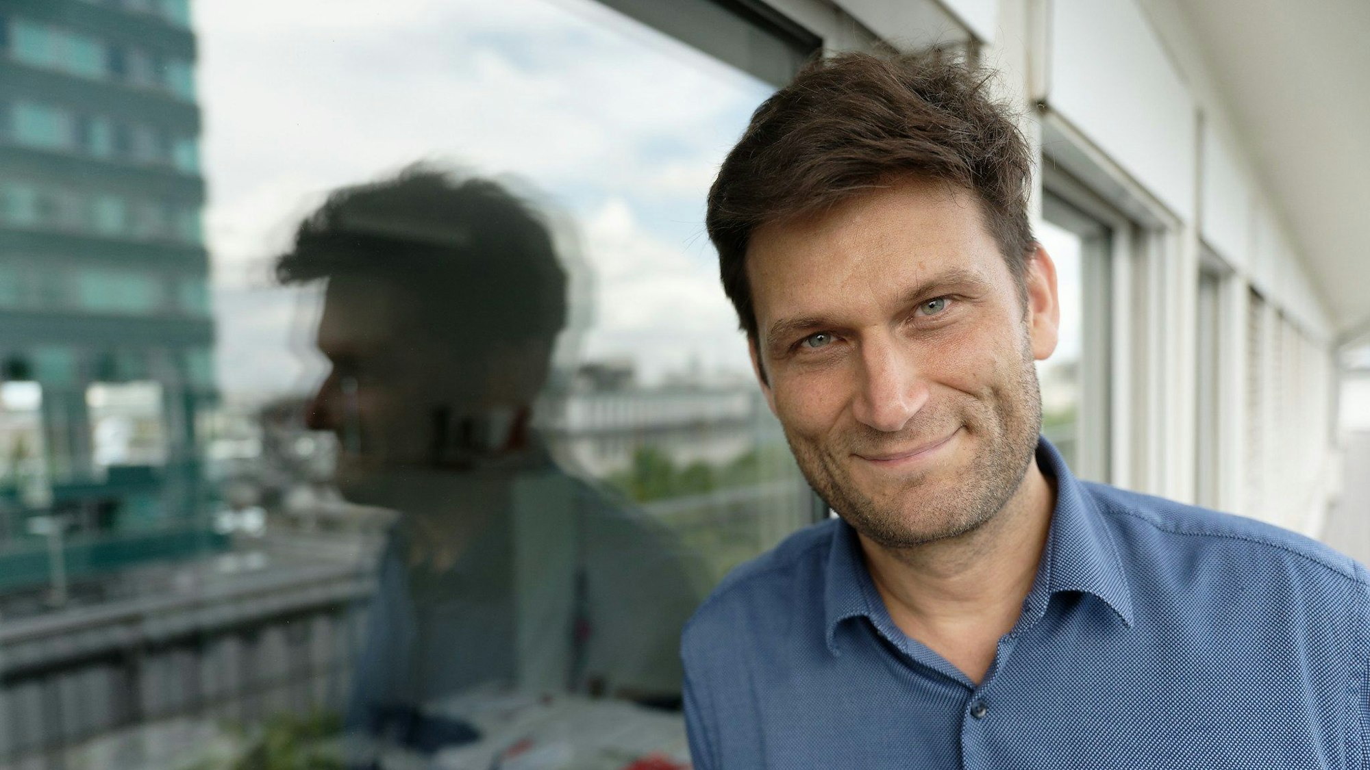 Der Fernsehmoderator, Kabarettist und Autor Christian Ehring steht auf einem Balkon.