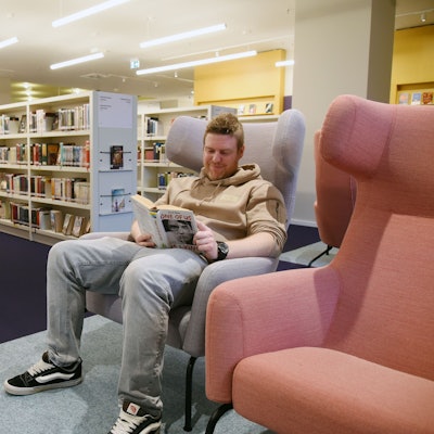 Bibliothekschef Christian Bürgin sitzt in einem Sessel und liest ein Buch.