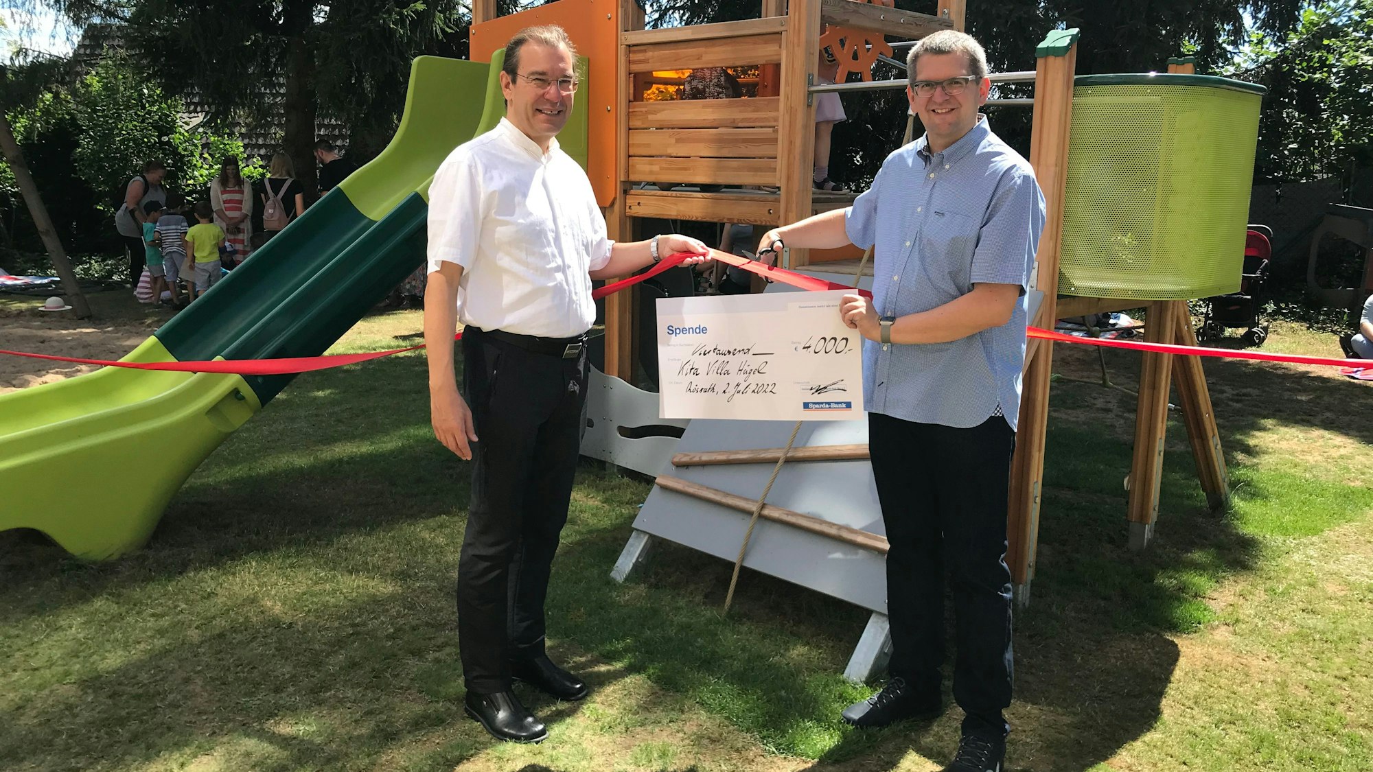 Zwei Männer halten einen Riesenscheck hoch und lächeln.