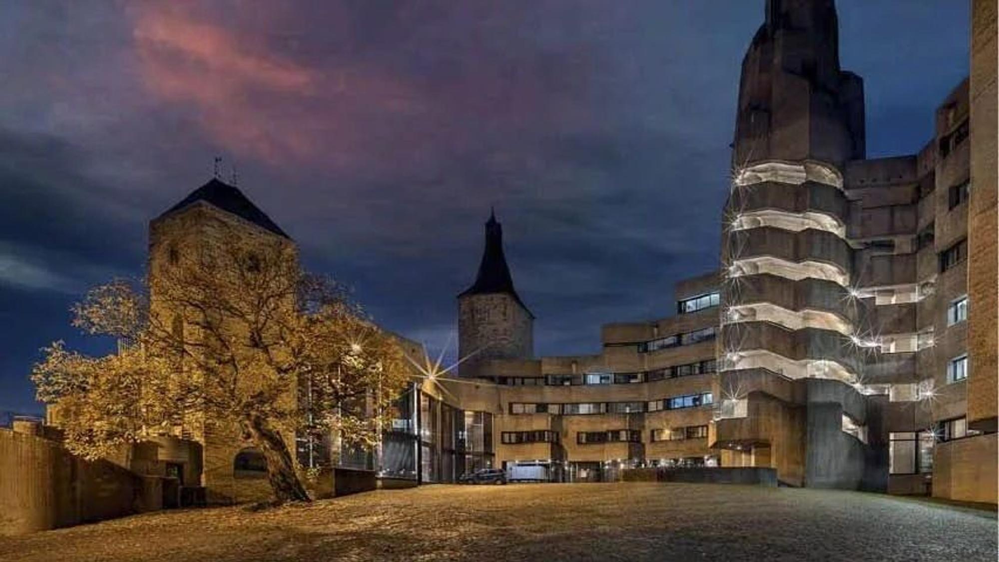 Ein u-förmiges Gebäude in der Nacht angestrahlt von Straßenlaternen.