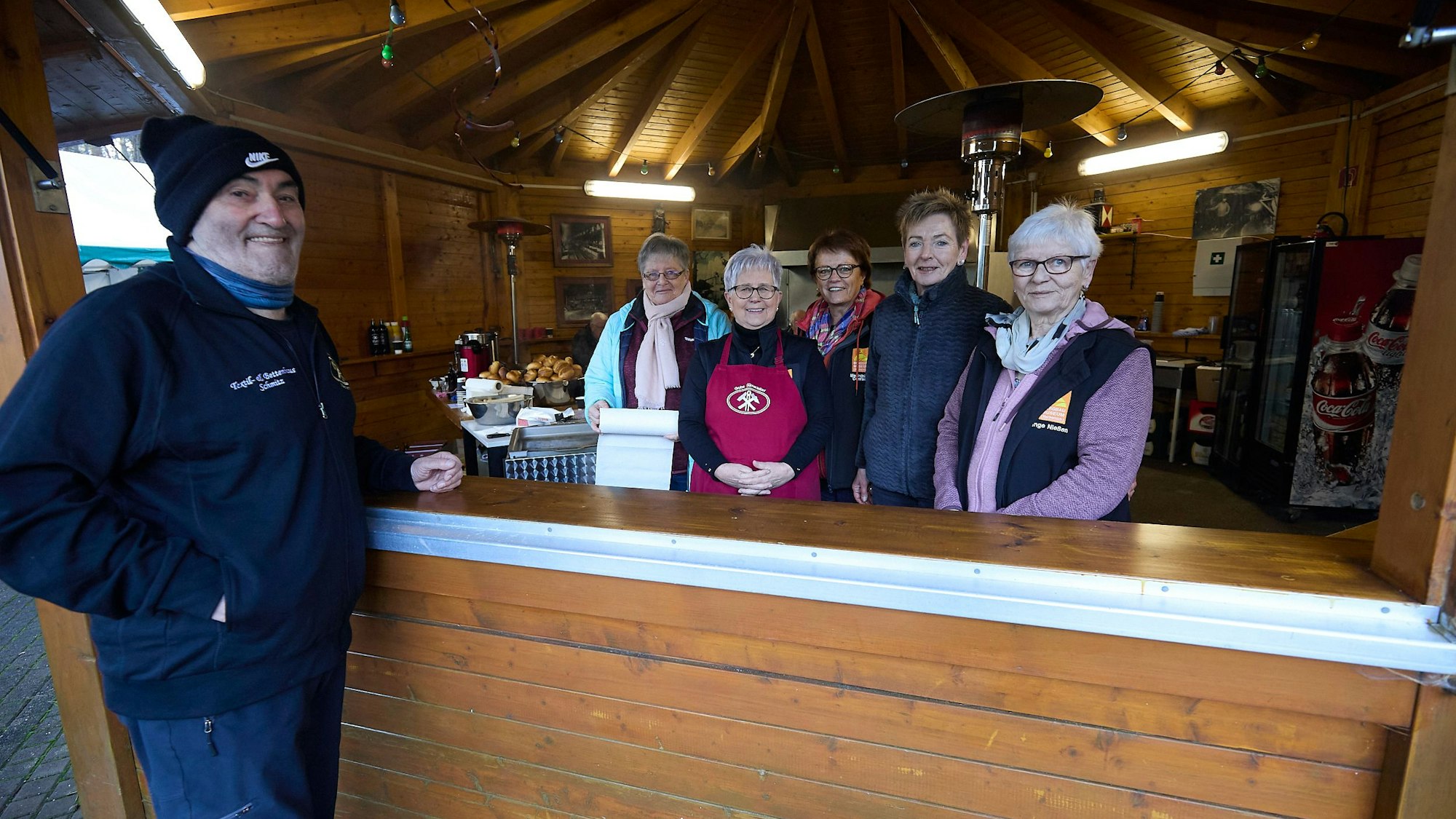 Vier Frauen stehen hinter einer Theke, ein Mann davor.