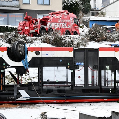 Der Bus liegt auf dem Dach. Zwei Mitarbeiter des Bergungstrupps begutachten das Wrack.