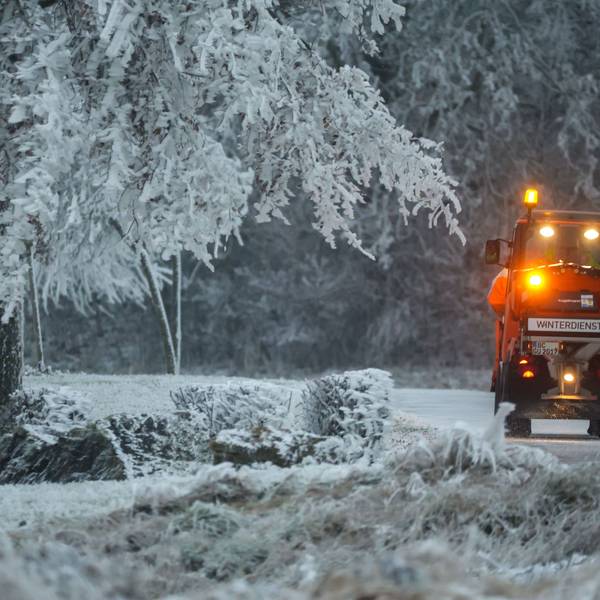 Ein Fahrzeug des Winterdienstes ist auf einer mit Schnee bedeckten Straße unterwegs