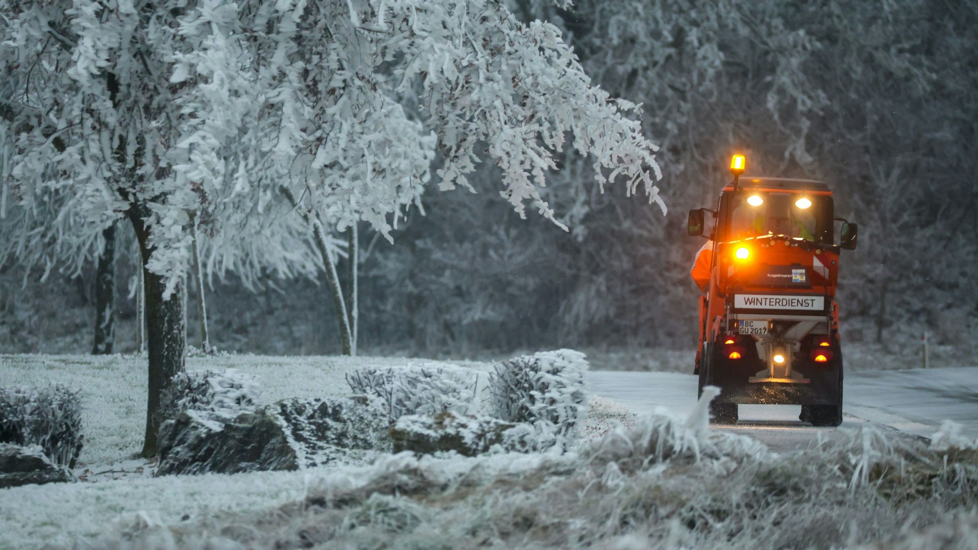 Ein Fahrzeug des Winterdienstes ist auf einer mit Schnee bedeckten Straße unterwegs