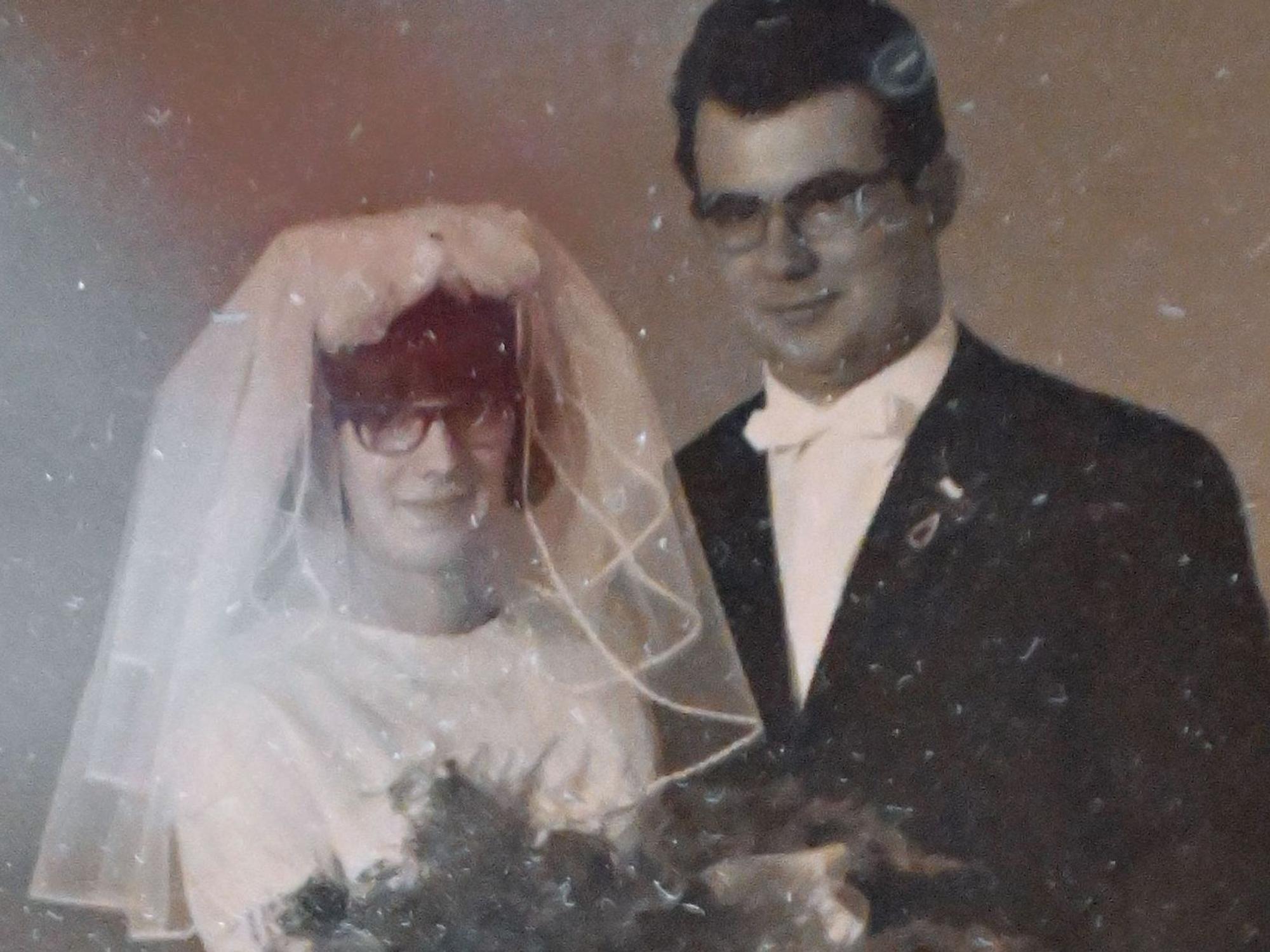 Auf dem Bild von der Hochzeit 1965 trägt die Braut einen Schleier und hält einen Blumenstrauß, der Bräutigam trägt einen schwarzen Anzug und eine weiße Fliege.