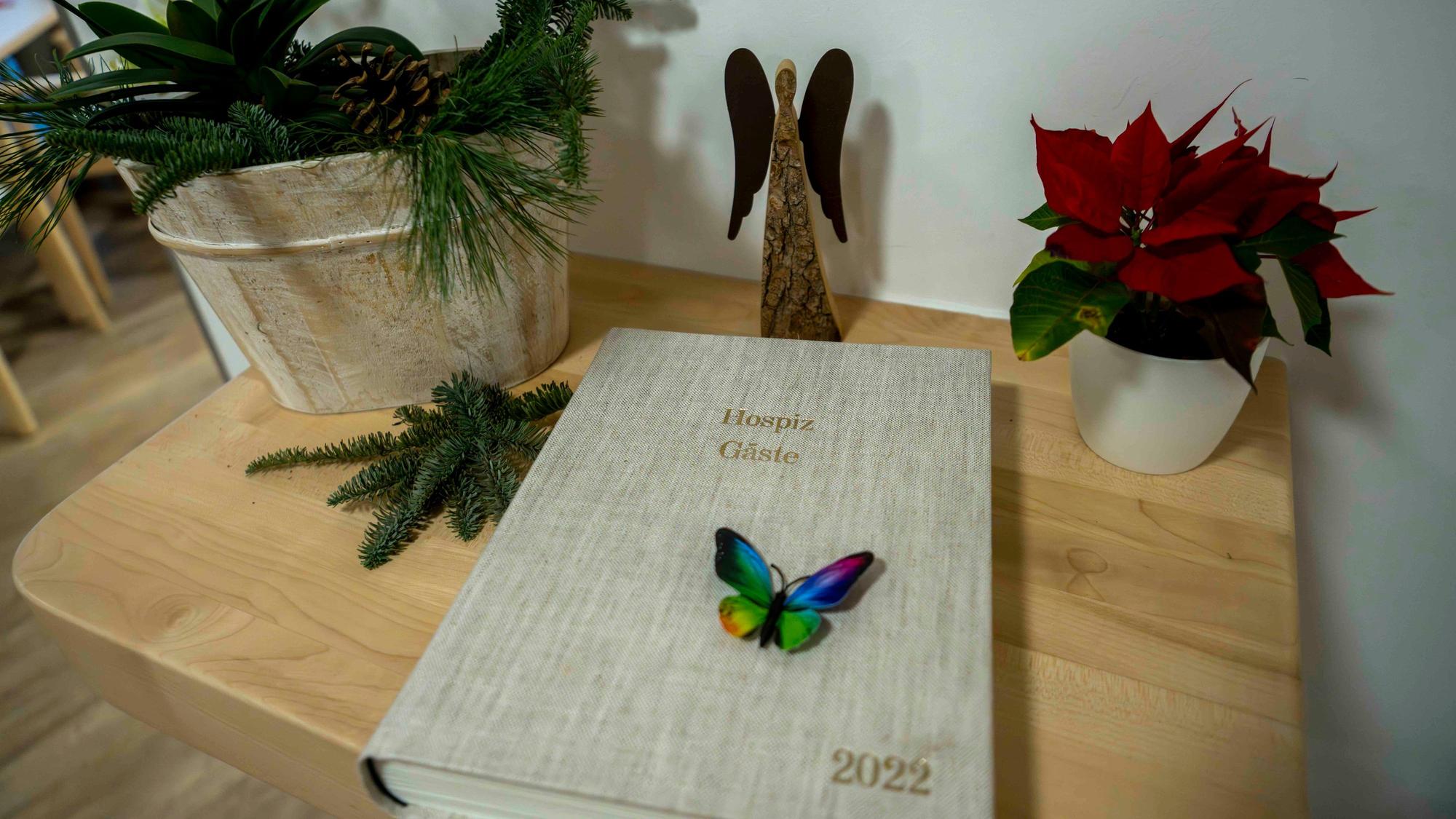 Das Bild zeigt ein Buch, das auf einem Tisch liegt. Zudem sind ein Engel aus Holz und ein Weihnachtsstern zu sehen.