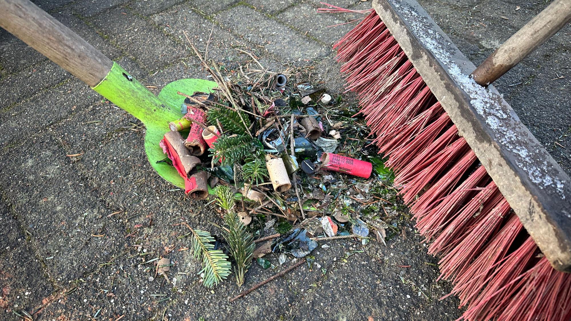 Eine Mischung aus Scherben, Knallerhülsen, Tannennadeln und kleinen Ästen wird sorgfältig zusammengekehrt.