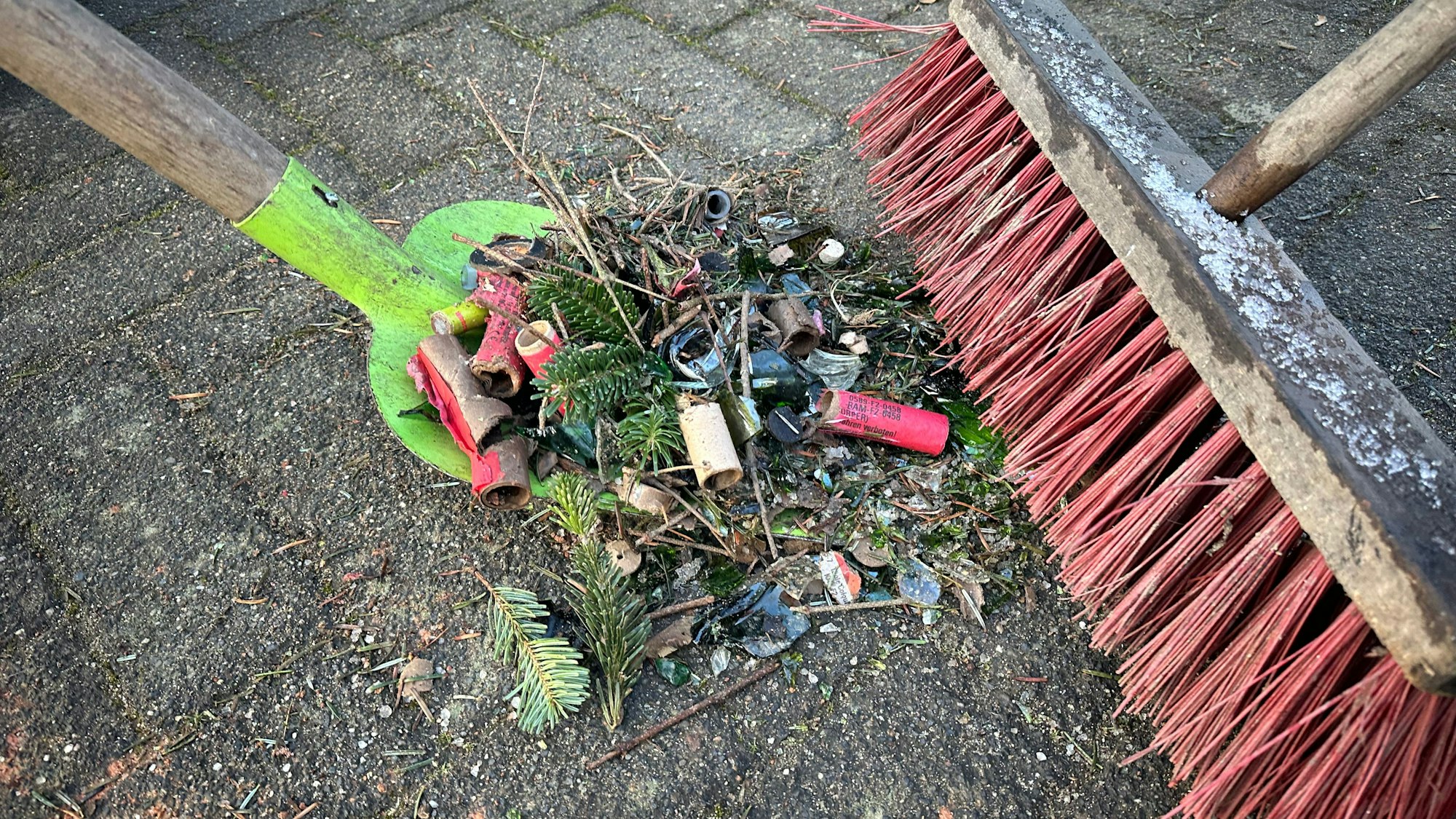 Eine Mischung aus Scherben, Knallerhülsen, Tannennadeln und kleinen Ästen wird sorgfältig zusammengekehrt.