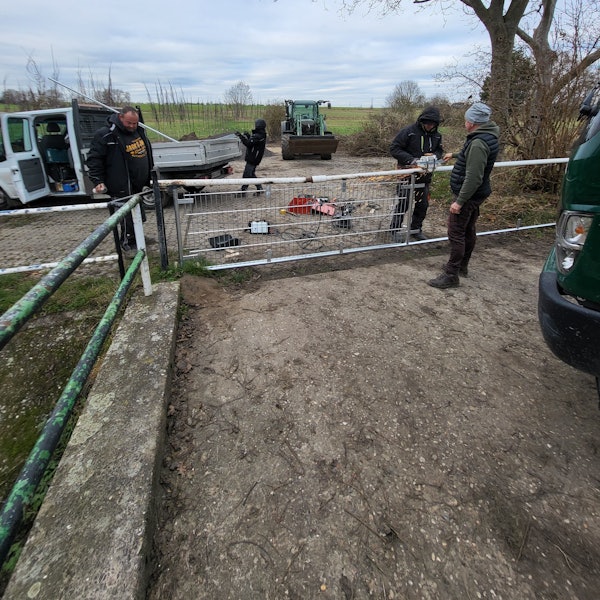 Drei Männer reparieren einen Zaun.