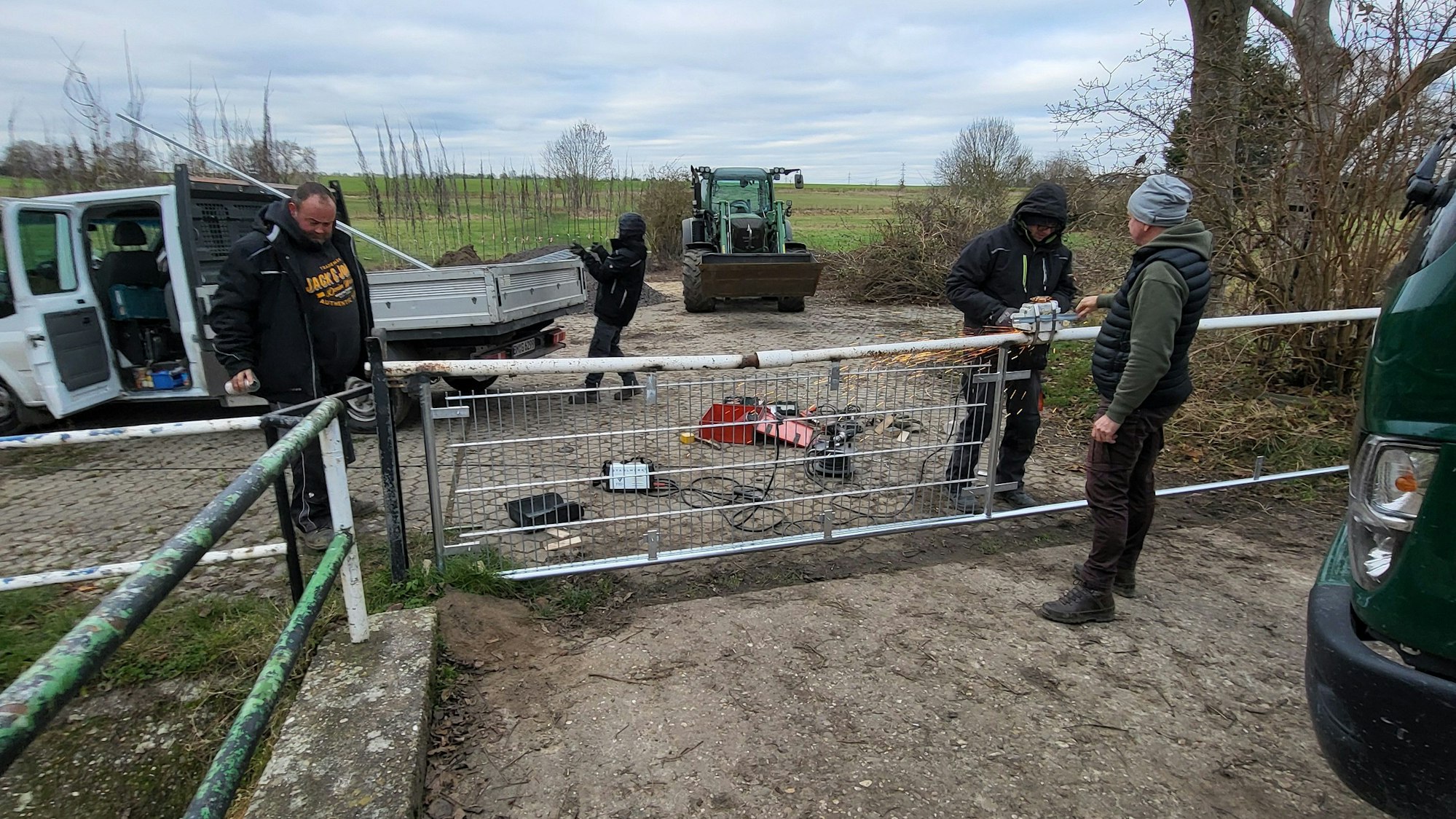 Drei Männer reparieren einen Zaun.