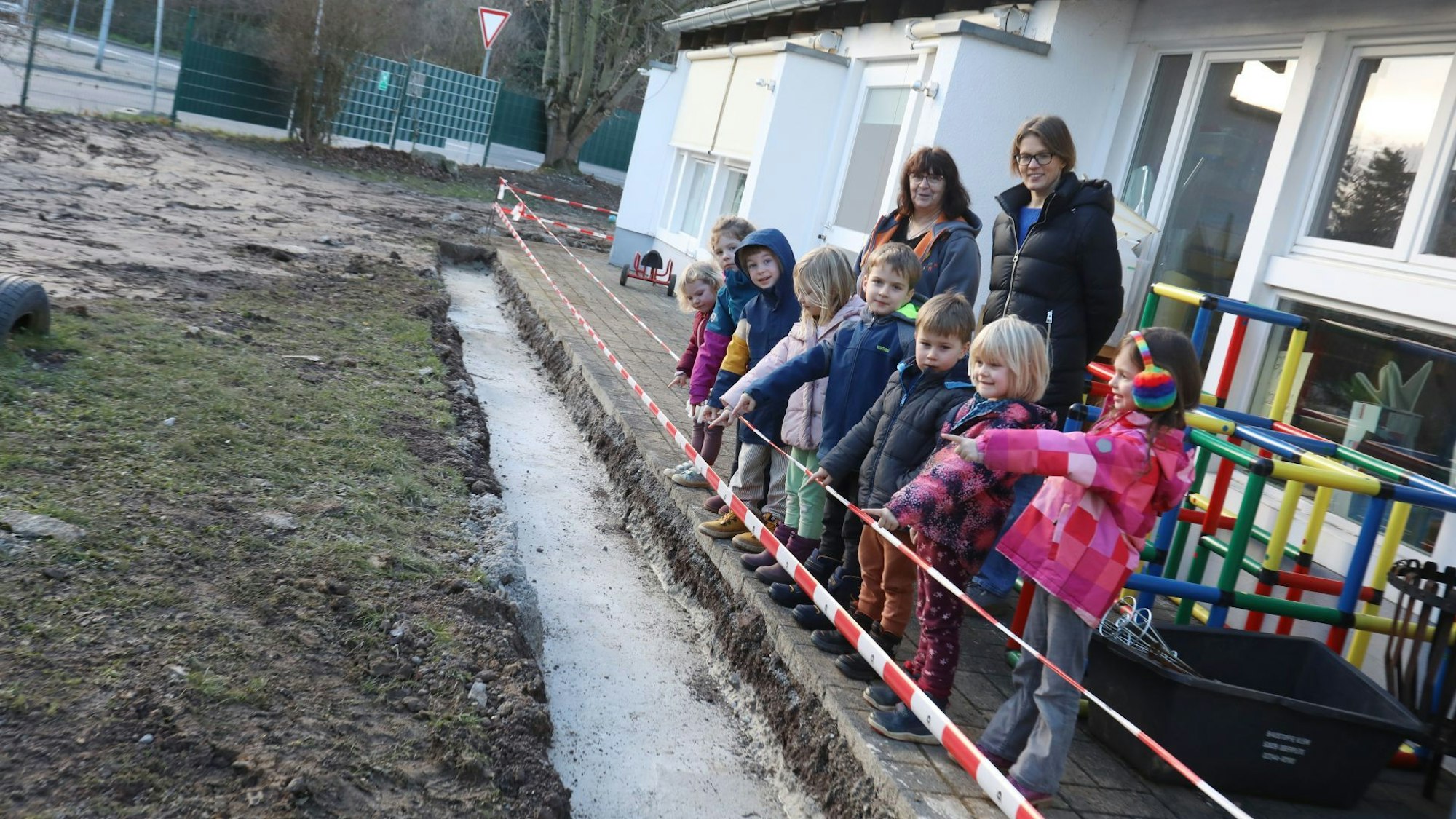 Eine Gruppe Kinder neben ihrer Kindertagesstätte.