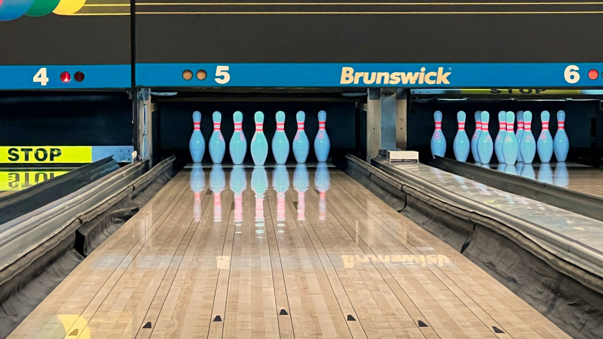 Pins stehen sortiert auf einer Bowling-Bahn.