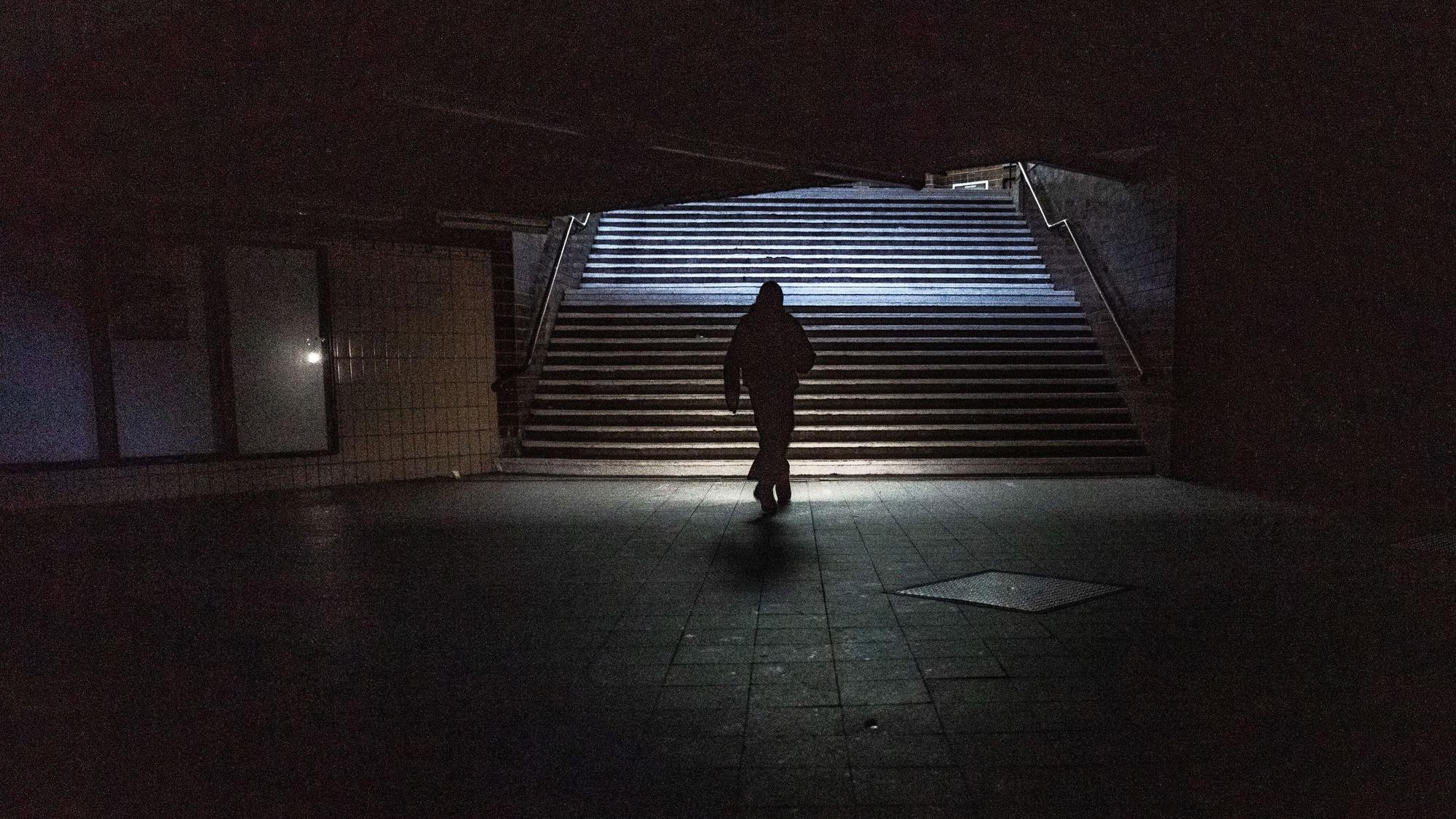 Das Foto zeigt eine Frau in einer Unterführung, in der das Licht ausgefallen ist.