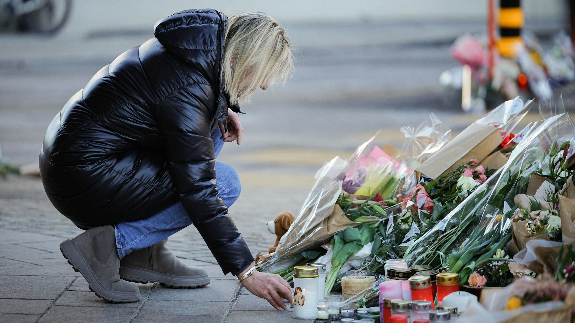 Trauer in der Schweiz: Eine Person kniet vor Blumen und Kerzen in Crans-Montana. In dem Ort hatte ein verheerendes Feuer in einer Bar während der Silvesternacht viele Tote und Verletzte gefordert. (Archivbild)