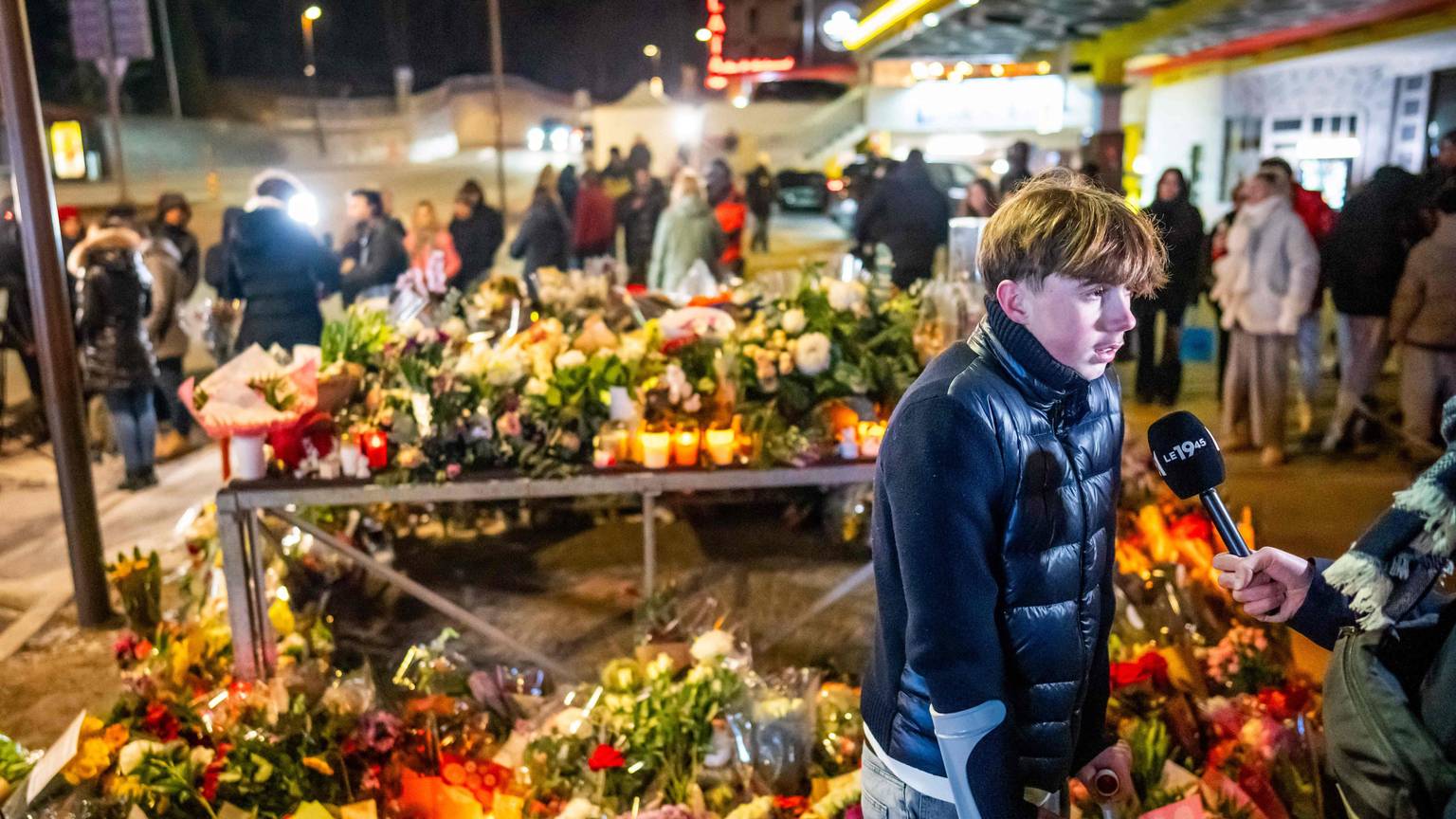 Ein junger Überlebender der Feuerkatastrophe spricht vor einem Blumenmeer in Crans-Montana mit Journalisten.