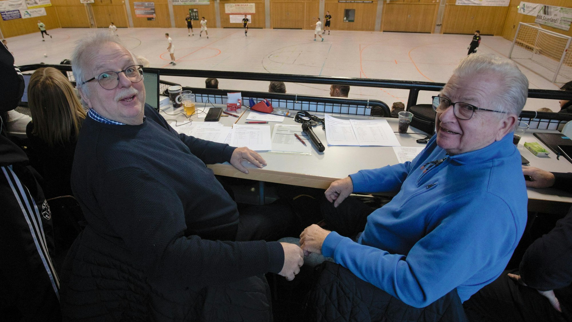 Zu sehen sind zwei Männer, die ein Fußballspiel beobachten.