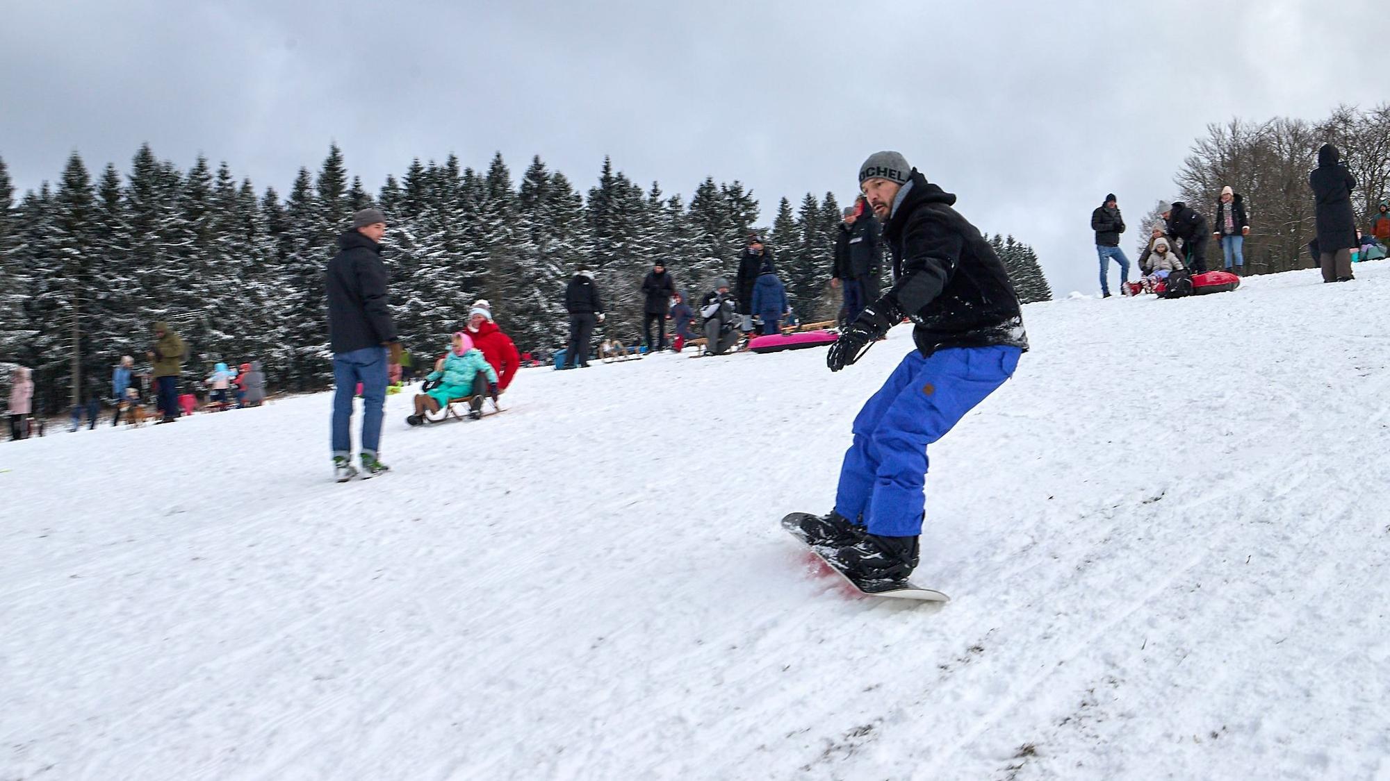 Ein Mann fährt auf einem Snowboard einen Hang hinunter.
