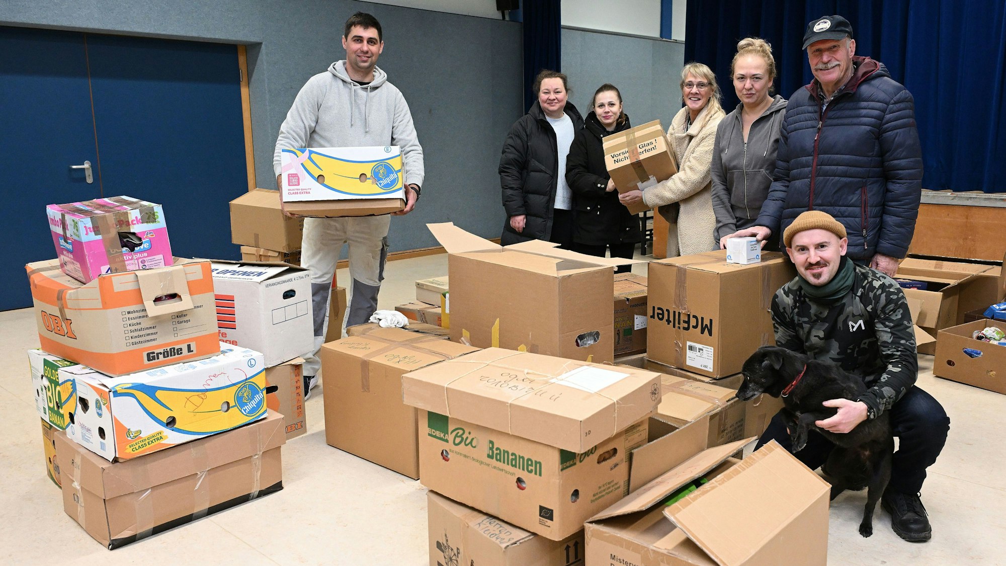 Die Helfer stehen inmitten von vielen Kartons.