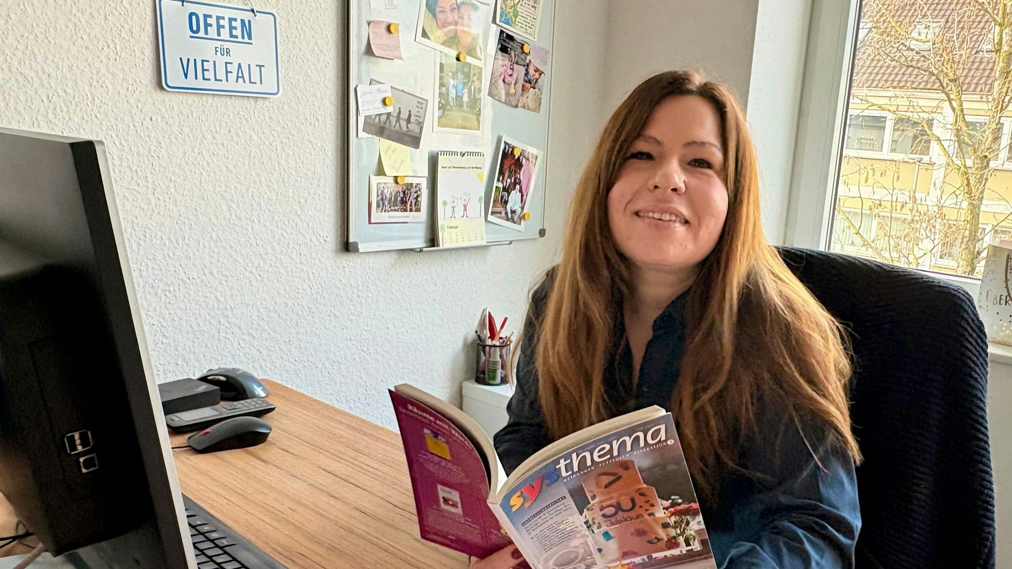 Sarah Eichhorst sitzt am Schreibtisch und hält eine Zeitschrift in den Händen.