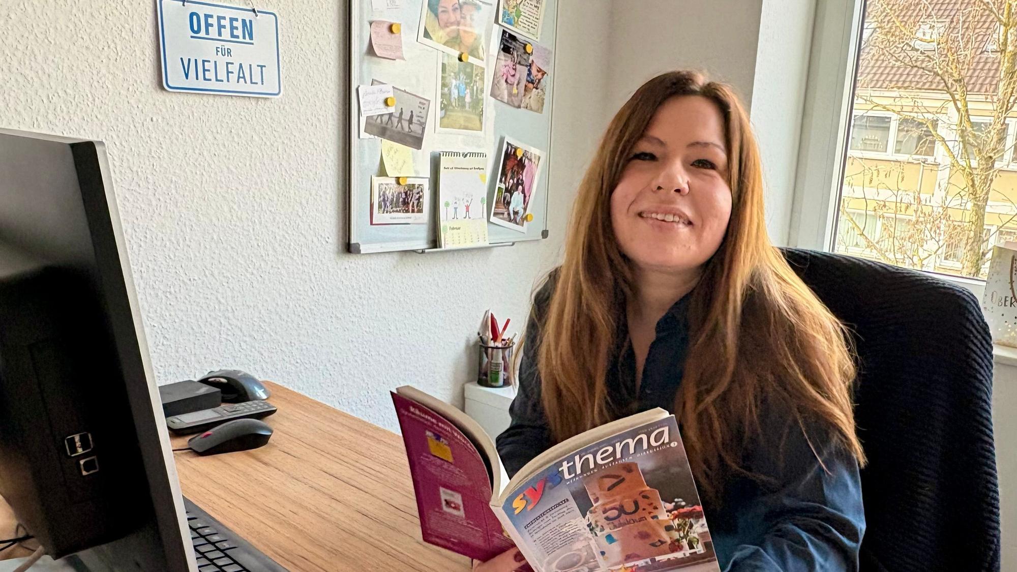 Sarah Eichhorst sitzt am Schreibtisch und hält eine Zeitschrift in den Händen.
