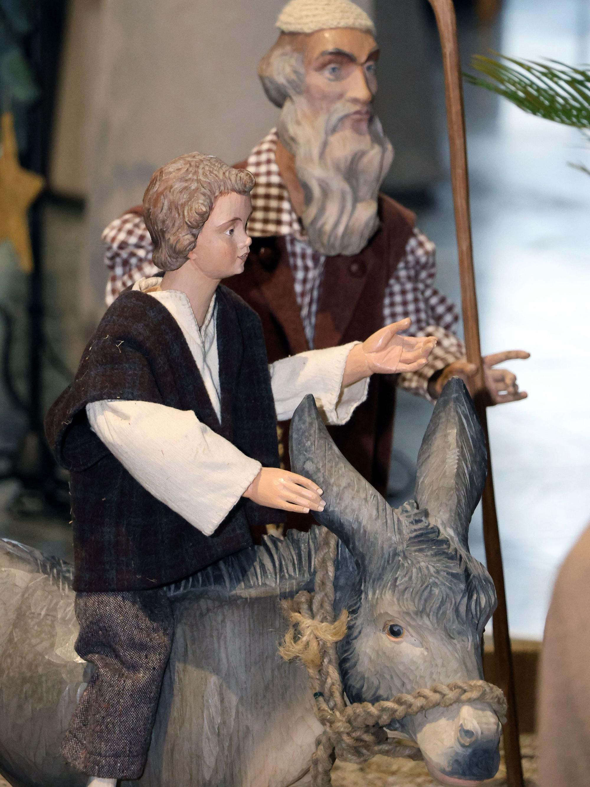 Auf dem Bild sind zwei Krippenfiguren und ein Holzesel zu sehen.