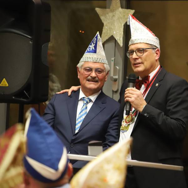 Reinhard Gotzen steht neben Bürgermeister Ulf Hürtgen. Der Bürgermeister hält ein Mikrofon in der linken Hand und hat seine rechte Hand auf Gotzens Schulter abgelegt.
