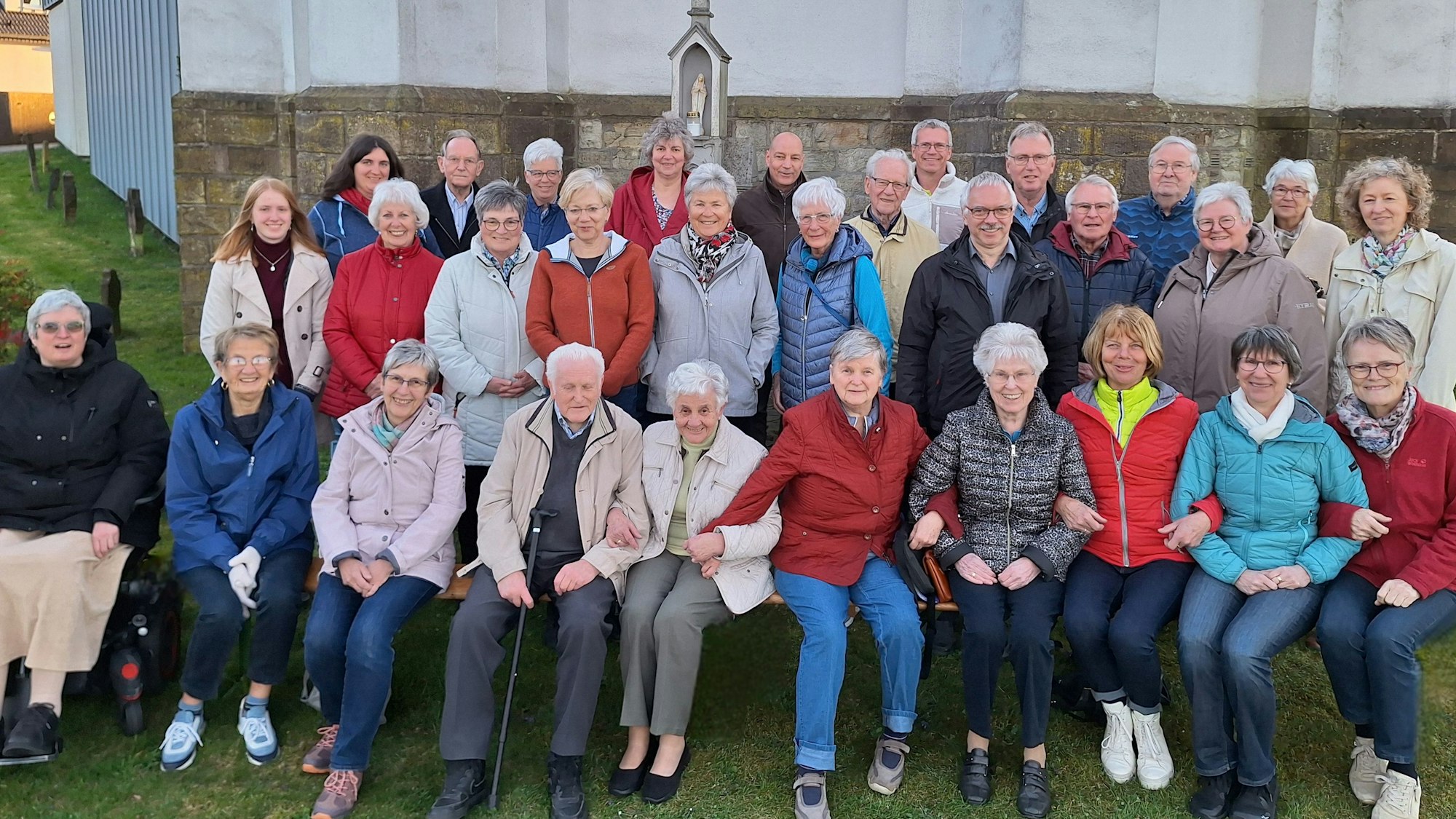 Die Mitglieder des Chors sitzen vor einer Kirche.