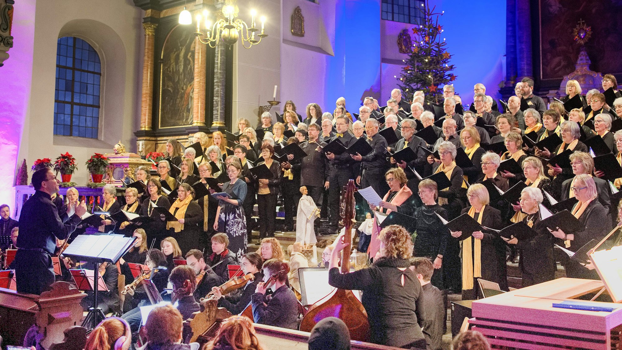 In der Kirche steht der gemischte Chor, davor sitzt das Orchester, der Dirigent steht an seinem Pult.