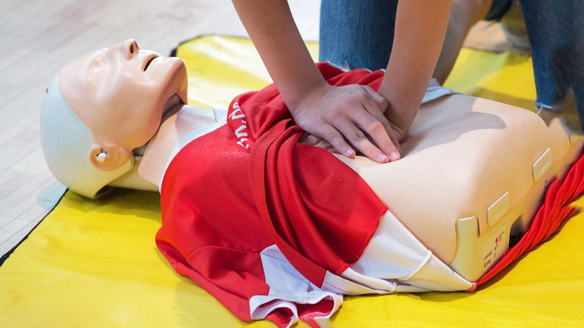 Das Bild zeigt einen Menschen, der an einer Puppe die Reanimation übt.