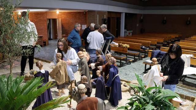 Auf dem Bild sind Ehrenamtler zu sehen, die in einer Kirche eine Krippe aufbauen.
