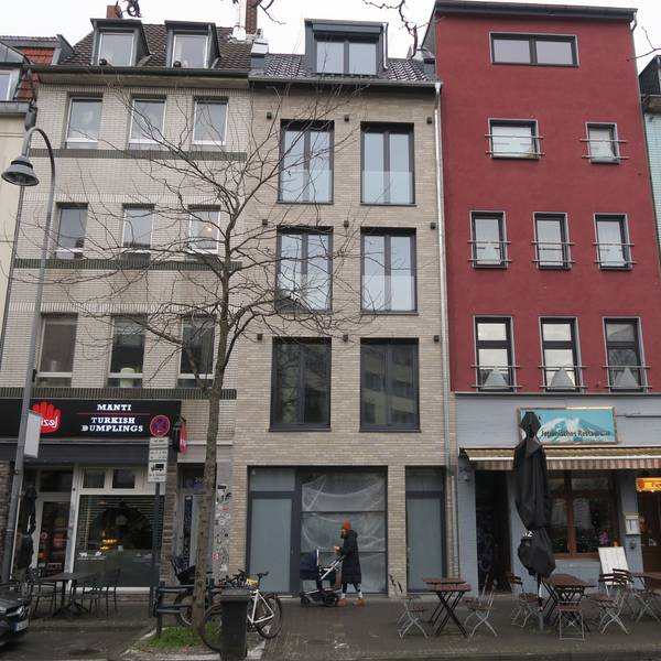 Eine Reihe Häuser an einer belebten Straße: Das Haus in der Mitte steht leer.