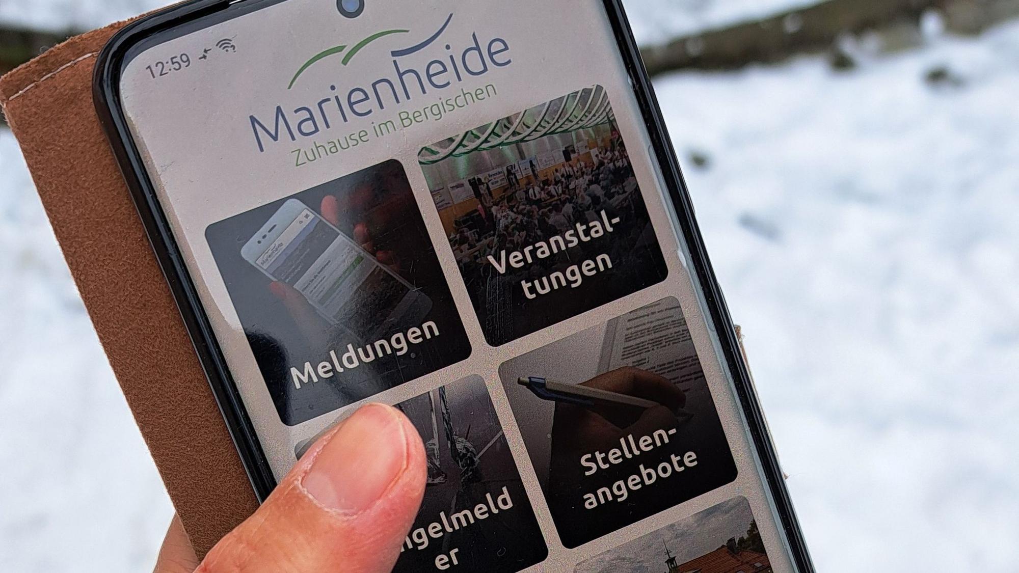 Das Foto zeigt ein Smartphone mit der Startseite der Marienheide-App.