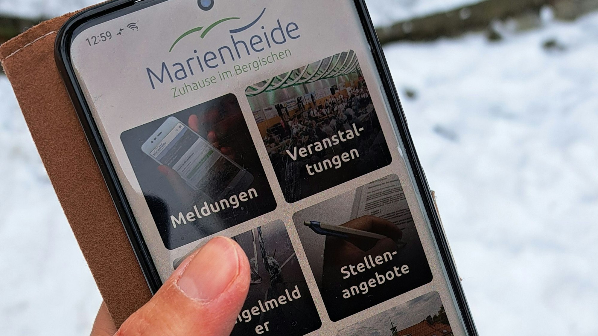 Das Foto zeigt ein Smartphone mit der Startseite der Marienheide-App.