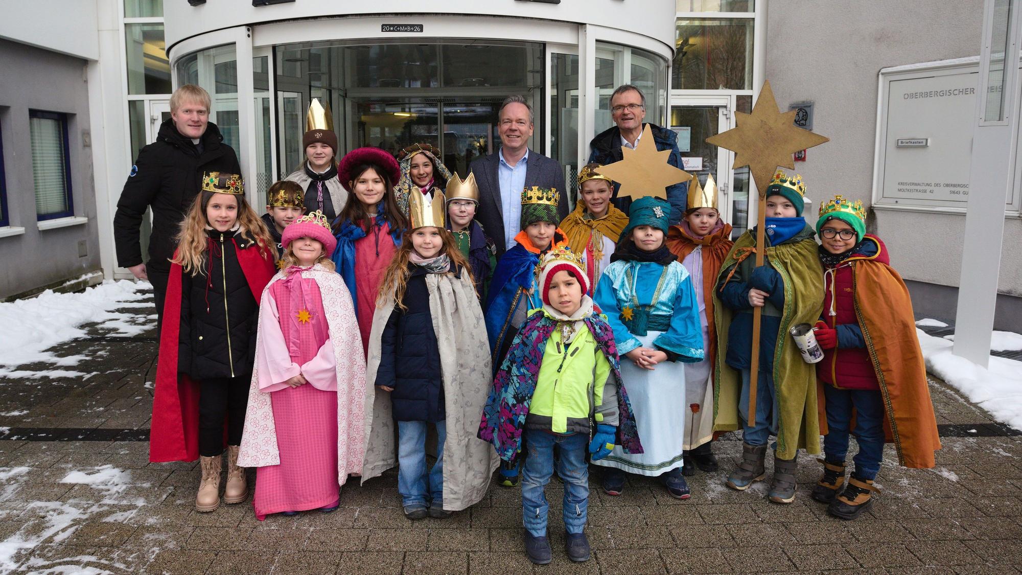 Die Sternsinger stehen mit dem Kaplan, dem Diakon und dem Landrat vor dem Eingang des Kreishauses.