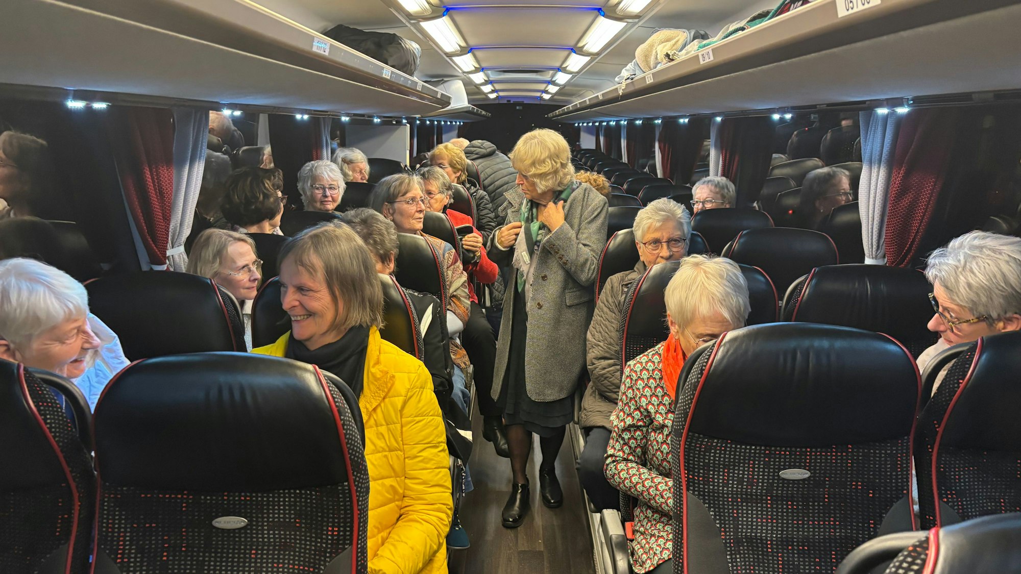 Ältere Frauen sitzen in einem Bus und reden miteinander.