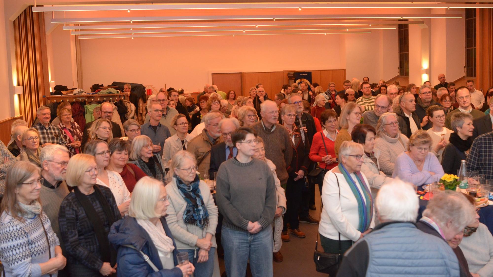 Die Menschen im Saal stehen dicht an dicht.
