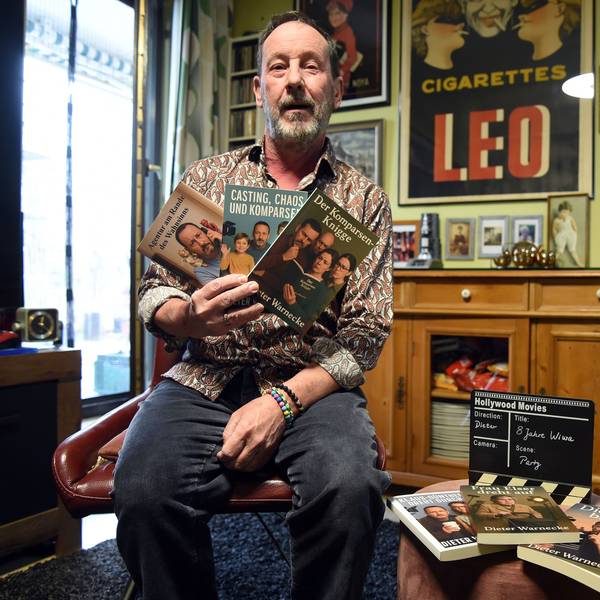Ein Mann hält drei Bücher in die Kamera.