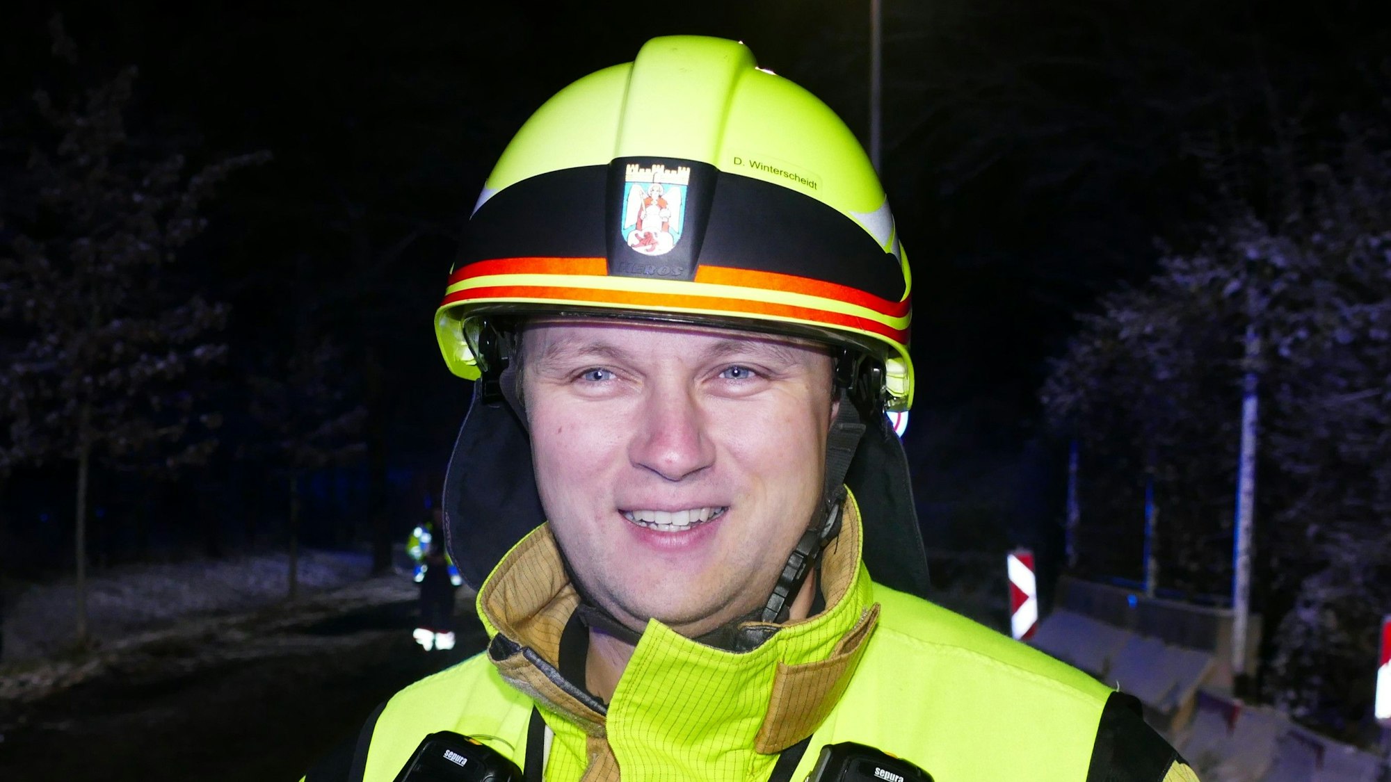 Ein Mann mit gelbem Feuerwehrhelm und einer gelb reflektierenden Jacke.