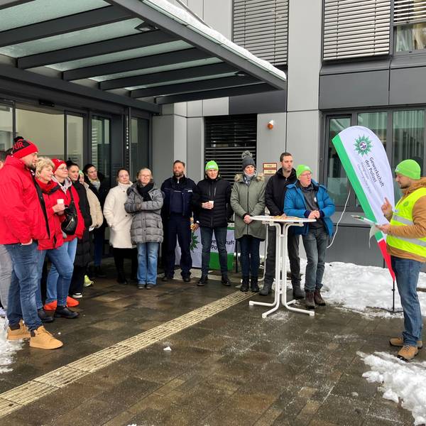 Eine Gruppe, darunter Gewerkschafter, steht vor dem Polizeigebäude in Gummersbach.