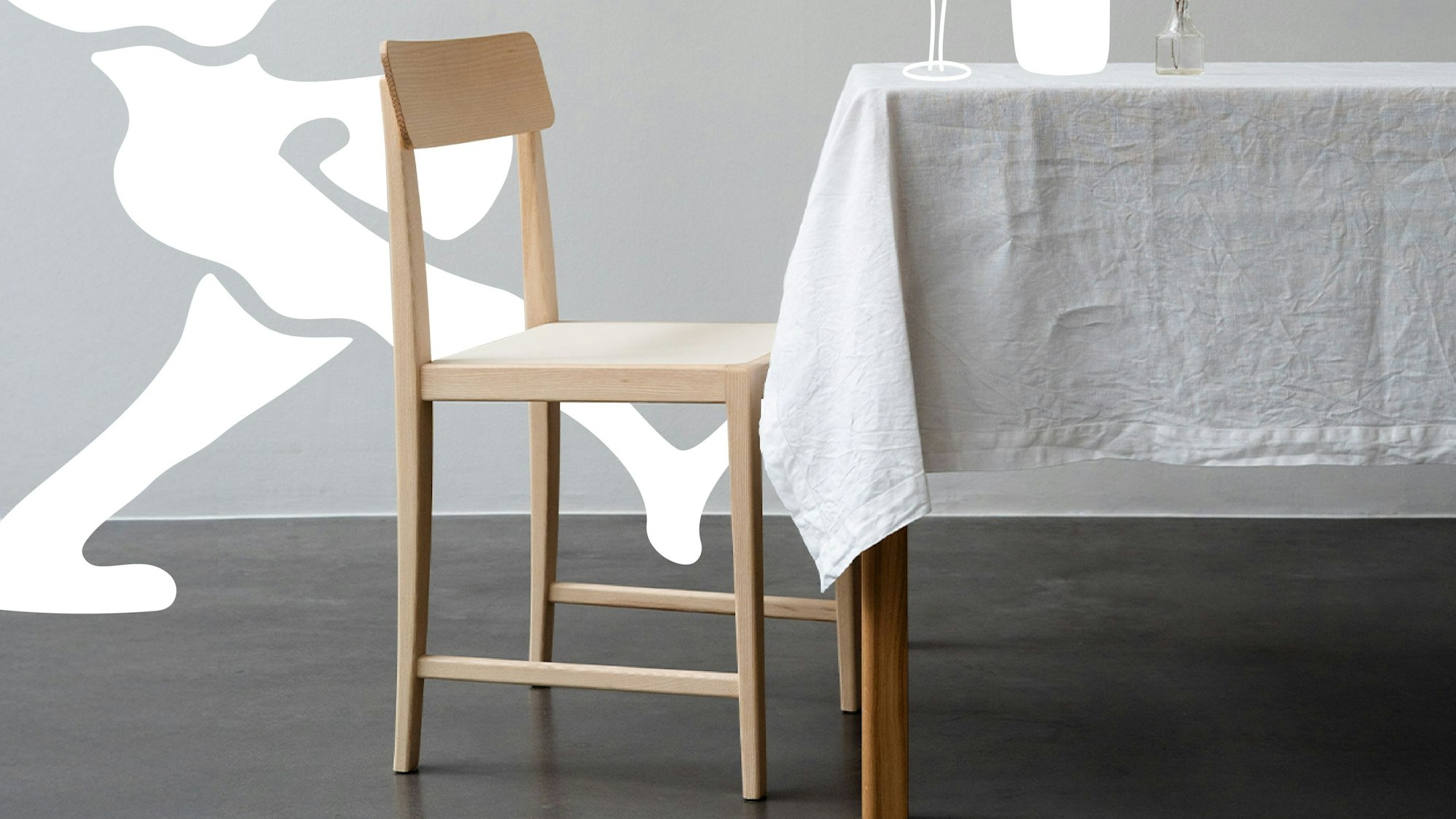 Ein schlichter Holzstuhl vor einem Tisch.