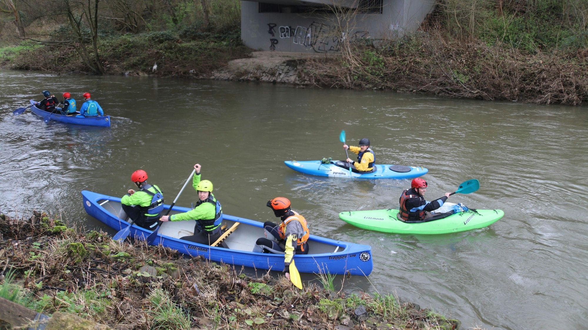 Personen in Kanus paddeln auf der Agger.
