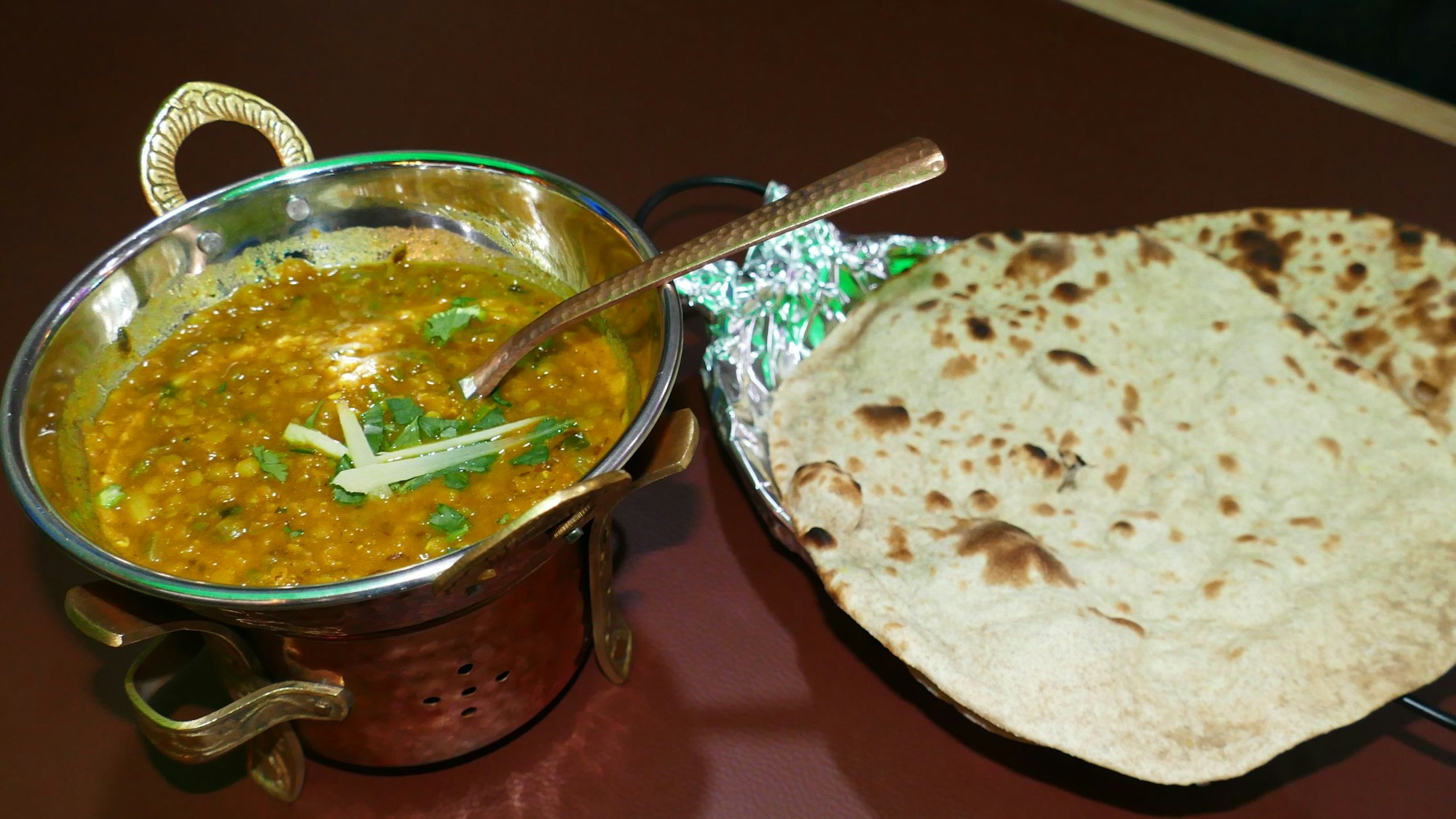 Eine kleine Schüssel mit einer Linsensuppe und ein Fladenbrot.
