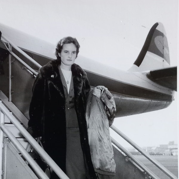 Eine junge Frau steigt in den 1950er Jahren aus einem Flugzeug.