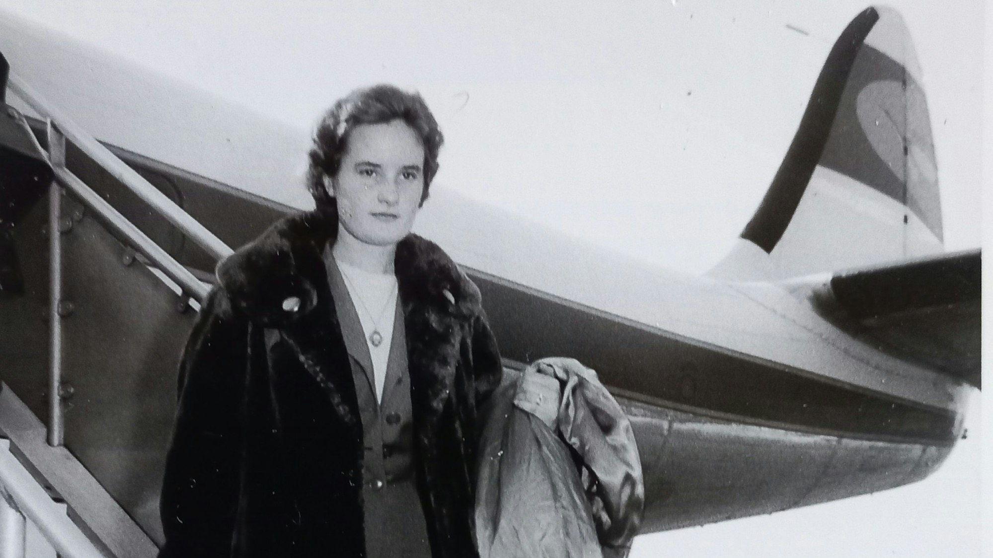 Eine junge Frau steigt in den 1950er Jahren aus einem Flugzeug.