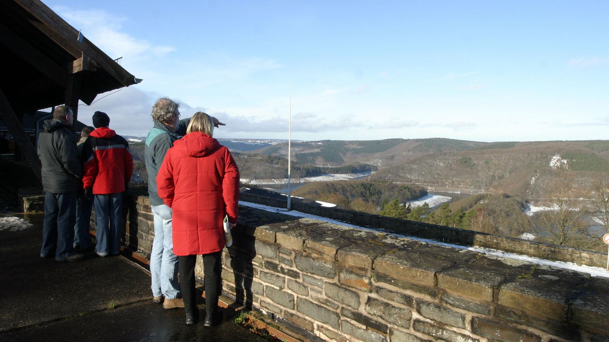 Menschen stehen an der Brüstung und schauen über den Urftsee.