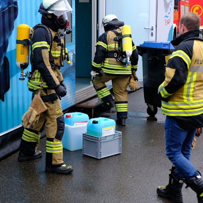 Drei Feuerwehrleute - zwei mit Atemschutz - haben Kanister mit einer Chlorgasflüssigkeit aus einem blauen Schwimmcontainer geborgen.